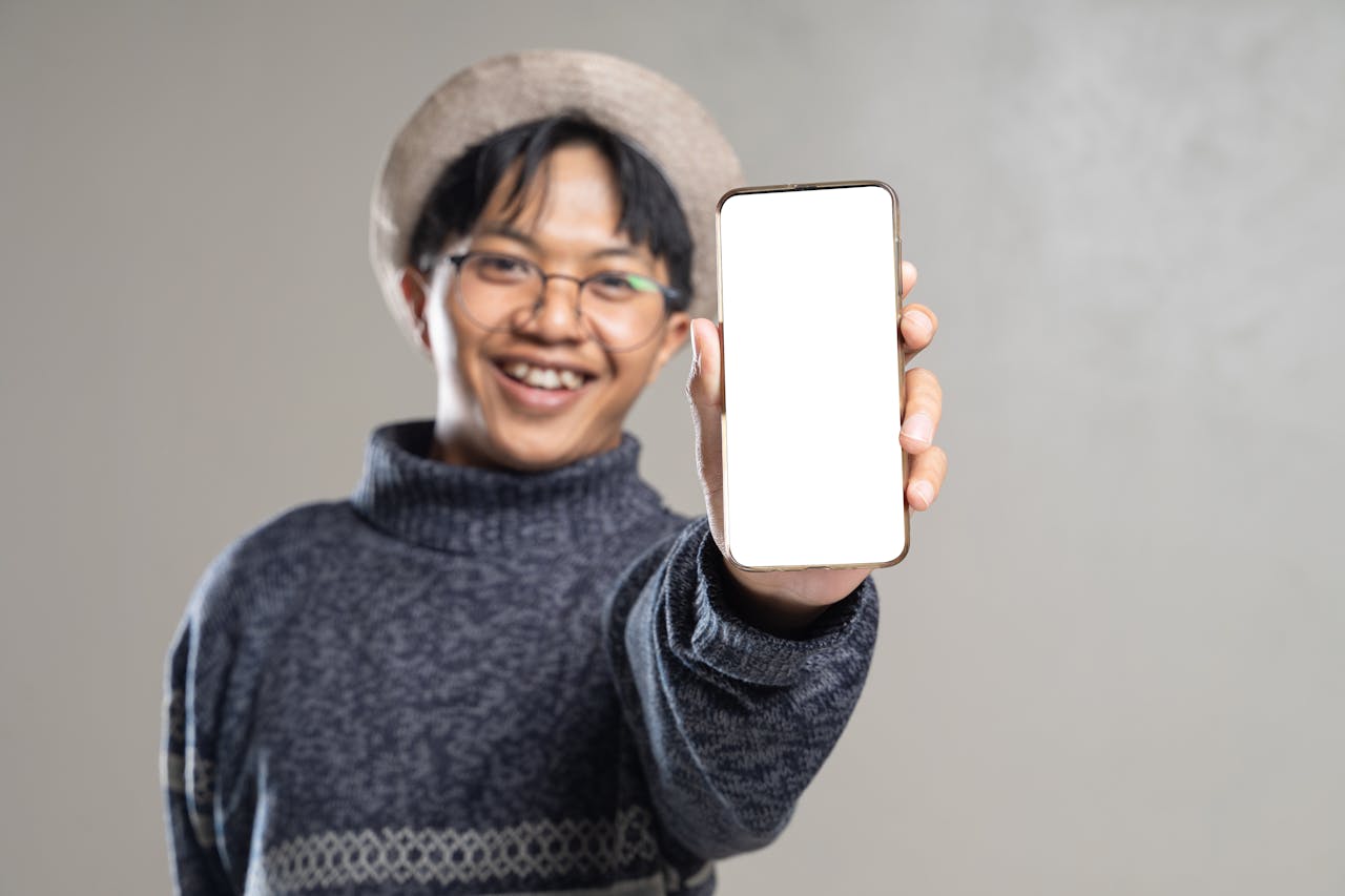 about-04 A cheerful young man displaying a smartphone with a blank screen, inviting customization.