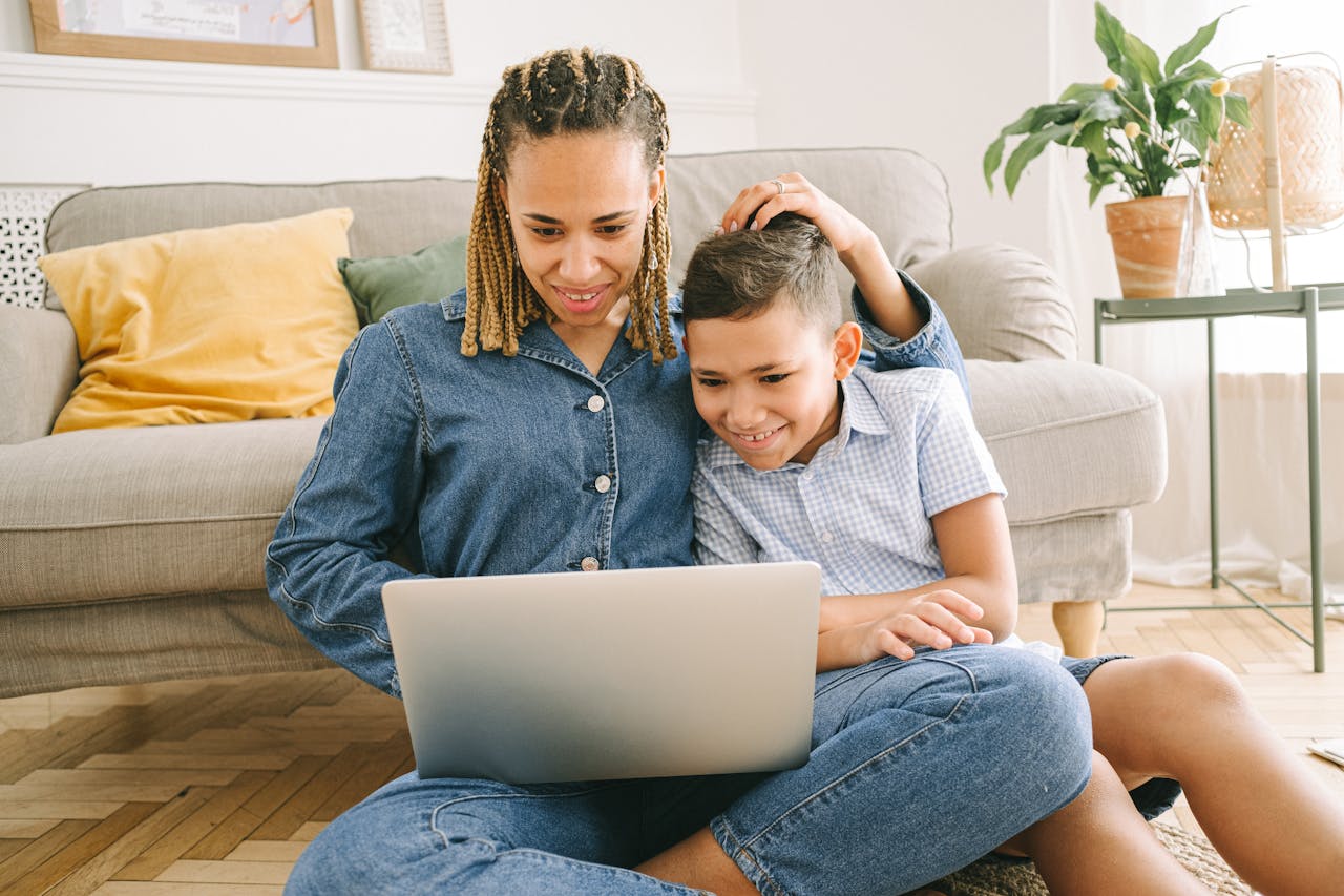 services-06 A loving mother and her son enjoying a fun time together while using a laptop indoors.