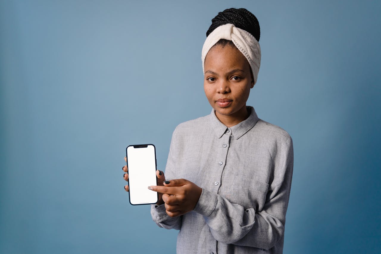 about-03 Confident woman displaying smartphone with blank screen against a blue backdrop.