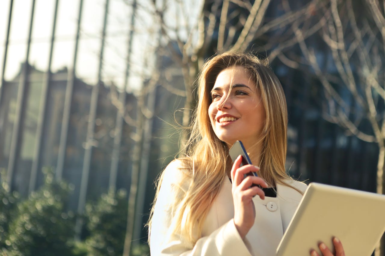 services-03 Smiling businesswoman holding smartphone and tablet outdoors in Milan.